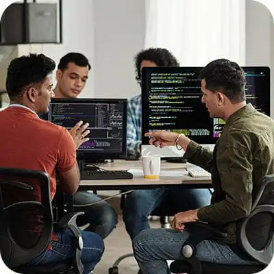 Team of developers collaborating at computers with code on screen