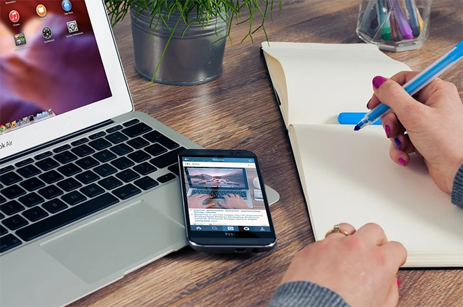 Writing blog content next to a laptop and phone